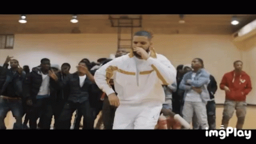 A Man Is Singing Into A Microphone While Dancing In Front Of A Crowd . GIF