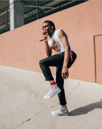 A Man Is Singing Into A Microphone While Kneeling Down GIF