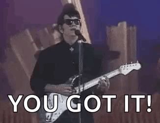 A Man Is Singing Into A Microphone While Playing A Guitar And Sunglasses . GIF