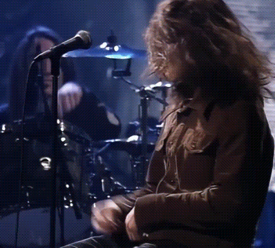 a man is singing into a microphone while playing drums