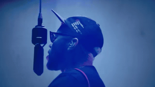 A Man Is Singing Into A Microphone With A Hat That Says ' I Love You ' On It GIF