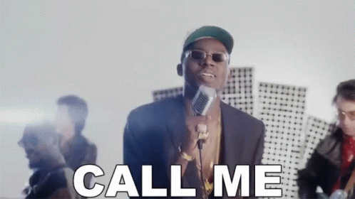 A Man Is Singing Into A Microphone With The Words Call Me Behind Him . GIF