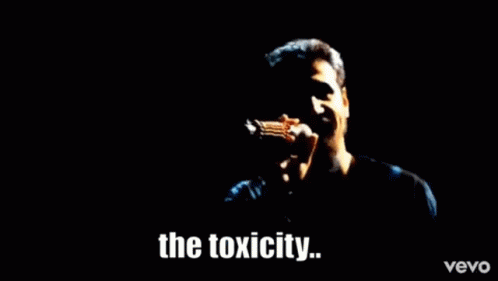 A Man Is Singing Into A Microphone With The Words The Toxicity Written Below Him GIF