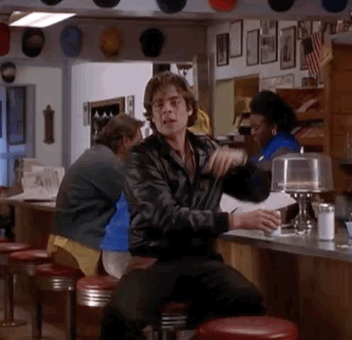 a man is sitting at a counter in a diner holding a cup of coffee .