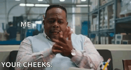 A Man Is Sitting At A Desk In A Warehouse Making A Funny Face While Talking To Someone . GIF
