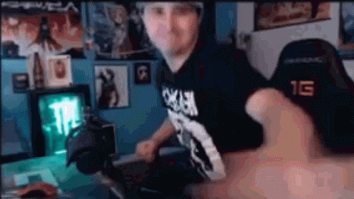 A Man Is Sitting At A Desk In Front Of A Computer In A Room . GIF