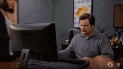 A Man Is Sitting At A Desk In Front Of A Computer With Nbc Written On The Screen GIF