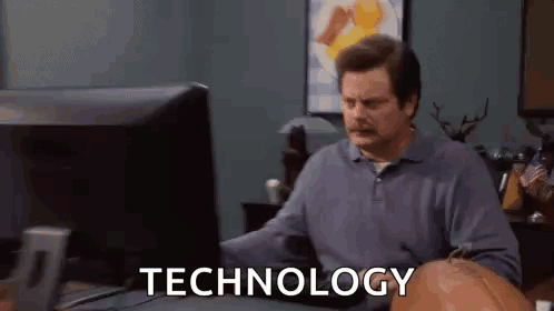 A Man Is Sitting At A Desk In Front Of A Computer With The Word Technology On The Screen . GIF