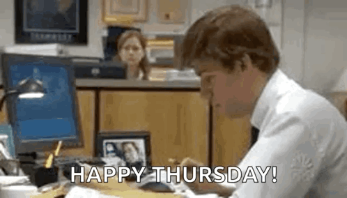 A Man Is Sitting At A Desk In Front Of A Computer With The Words `` Happy Thursday '' Written On The Screen . GIF