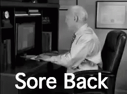 A Man Is Sitting At A Desk In Front Of A Computer With The Words `` Sore Back '' Written On It . GIF