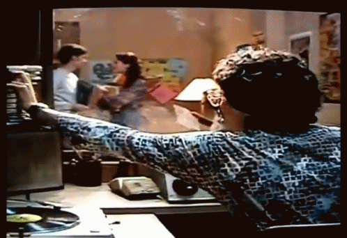 A Man Is Sitting At A Desk Looking At A Tv Screen GIF