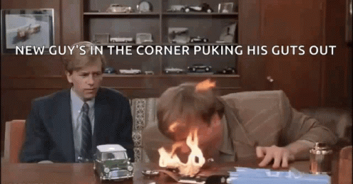 A Man Is Sitting At A Desk With A Toy Car On Fire . GIF