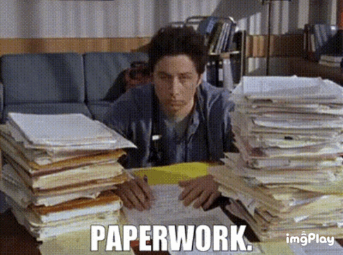A Man Is Sitting At A Desk With Stacks Of Papers And The Word Paperwork Written On The Screen GIF