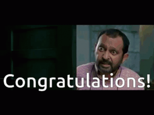 A Man Is Sitting At A Desk With The Words Congratulations Written On The Screen GIF