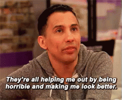 a man is sitting at a table and says they 're all helping me out by being horrible