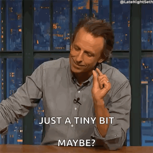 A Man Is Sitting At A Table And Smiling And Says Just A Tiny Bit Maybe GIF