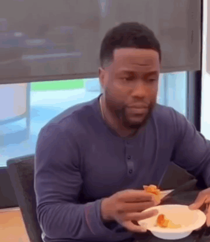 a man is sitting at a table eating a slice of pizza .
