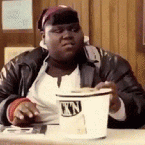 A Man Is Sitting At A Table Holding A Cup That Says ' Nn ' On It GIF