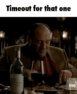 A Man Is Sitting At A Table Holding A Glass Of Wine . GIF