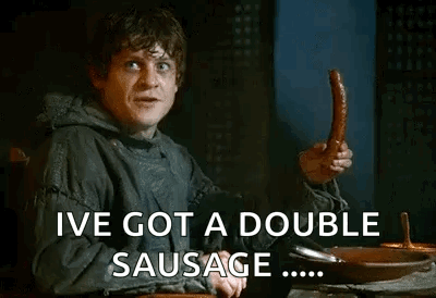 A Man Is Sitting At A Table Holding A Sausage And Saying `` Ive Got A Double Sausage '' . GIF
