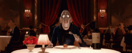 A Man Is Sitting At A Table In A Restaurant Eating A Piece Of Cake . GIF