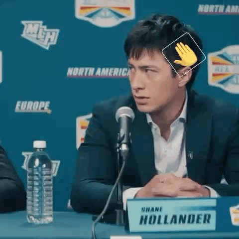 A Man Is Sitting At A Table In Front Of A Microphone . GIF