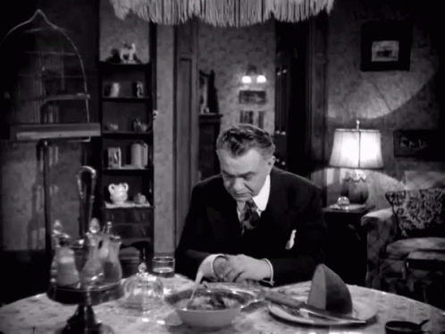 A Man Is Sitting At A Table With A Bowl Of Food GIF