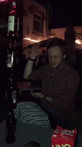 A Man Is Sitting At A Table With A Box Of Uno Chips GIF