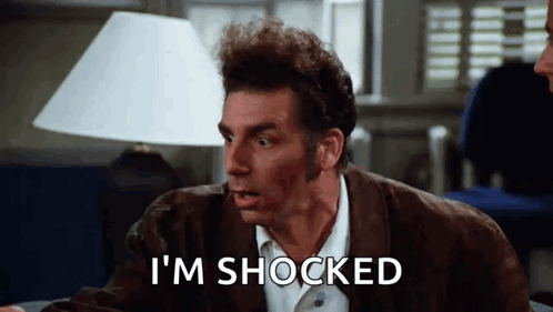 A Man Is Sitting At A Table With A Lamp And Says `` I 'M Shocked '' . GIF
