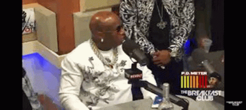 A Man Is Sitting At A Table With A Microphone In Front Of Him . GIF