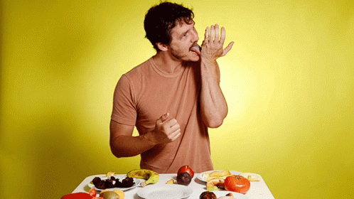 A Man Is Sitting At A Table With A Plate Of Food GIF