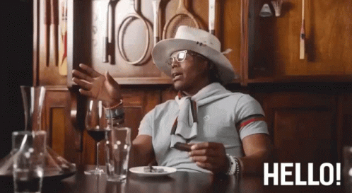 A Man Is Sitting At A Table With A Plate Of Food And A Glass Of Wine And The Words Hello Behind Him GIF