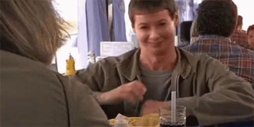A Man Is Sitting At A Table With A Straw In His Glass . GIF