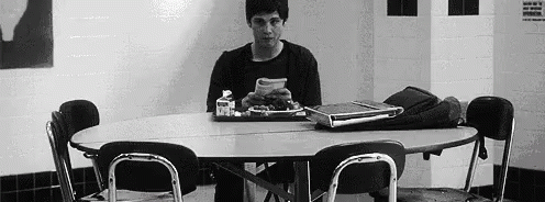 A Man Is Sitting At A Table With A Tray Of Food . GIF