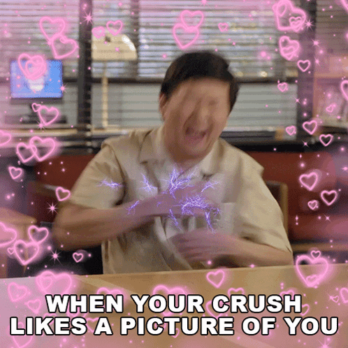 A Man Is Sitting At A Table With Hearts Around Him And The Caption Says When Your Crush Likes A Picture Of You GIF
