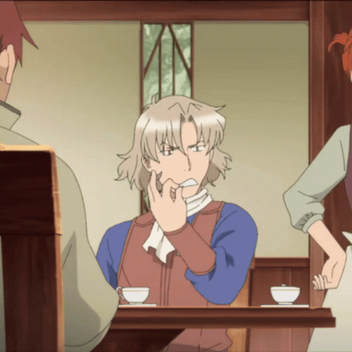 A Man Is Sitting At A Table With His Hand On His Mouth GIF