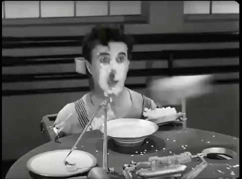 A Man Is Sitting At A Table With Plates And A Bowl Of Food GIF