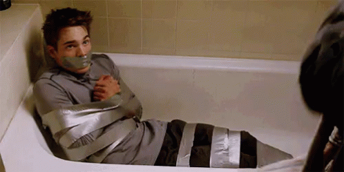 A Man Is Sitting In A Bathtub With Tape On His Mouth . GIF
