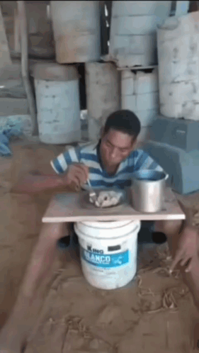 A Man Is Sitting In A Bucket Of King Blanco Paint GIF