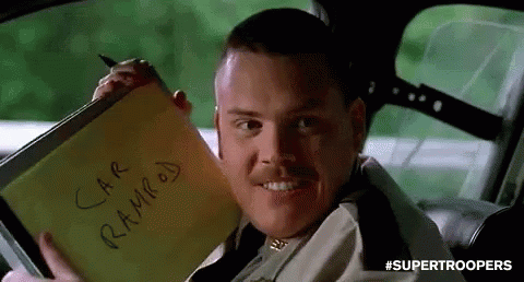 A Man Is Sitting In A Car Holding A Notepad That Says `` Car Ramped '' On It . GIF