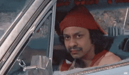 A Man Is Sitting In A Car Wearing A Red Hat . GIF