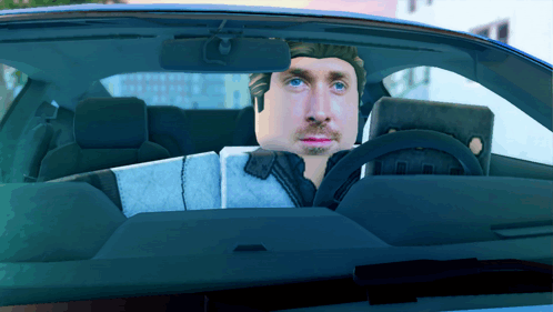 A Man Is Sitting In A Car With A Laptop On His Lap GIF