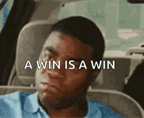 A Man Is Sitting In A Car With The Words A Win Is A Win Written Above Him . GIF