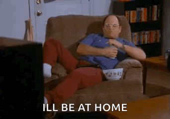 A Man Is Sitting In A Chair Eating Popcorn And Drinking Beer While Watching Television . GIF