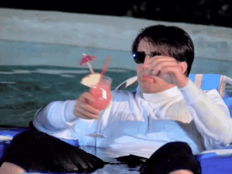 A Man Is Sitting In A Chair Holding A Drink In His Hand GIF