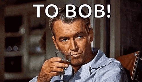 A Man Is Sitting In A Chair Holding A Glass Of Whiskey And Smoking A Cigarette . GIF