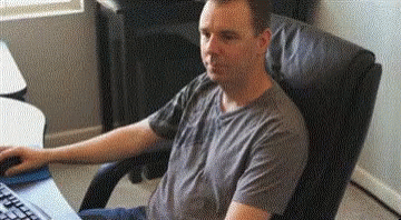 A Man Is Sitting In A Chair In Front Of A Computer Keyboard . GIF