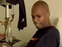 A Man Is Sitting In A Chair In Front Of A Table With Candles And A Bottle Of Water . GIF