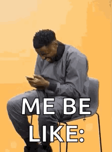 A Man Is Sitting In A Chair Looking At His Cell Phone And Saying `` Me Be Like '' . GIF