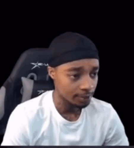 A Man Is Sitting In A Chair Wearing A Headband And A White Shirt . GIF